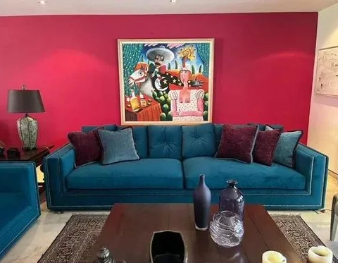 Sala con sofá de terciopelo azul tapizado a medida y obra de arte sobre muro intenso
