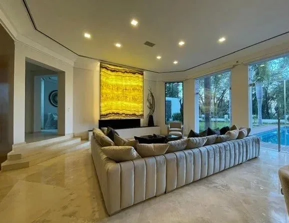 Sala amplia con sofá modular dorado frente a ventanales y alberca