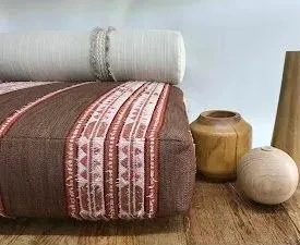 Cojines y tapizado artesanal con detalles bordados sobre madera natural